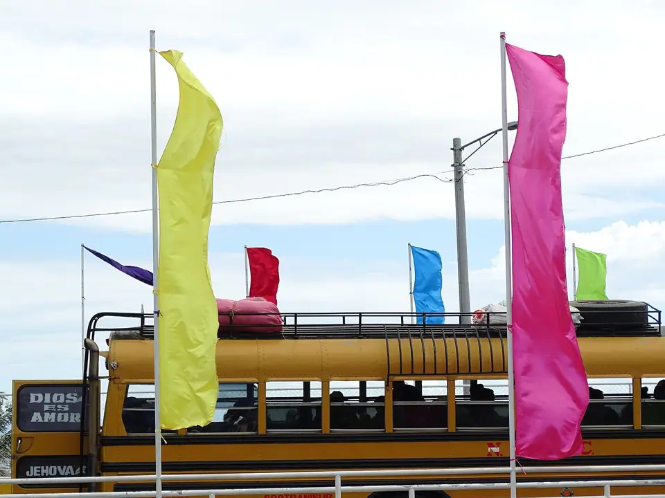 Bus Blue Bird con banderines y bultos en el techo, en San Jorge